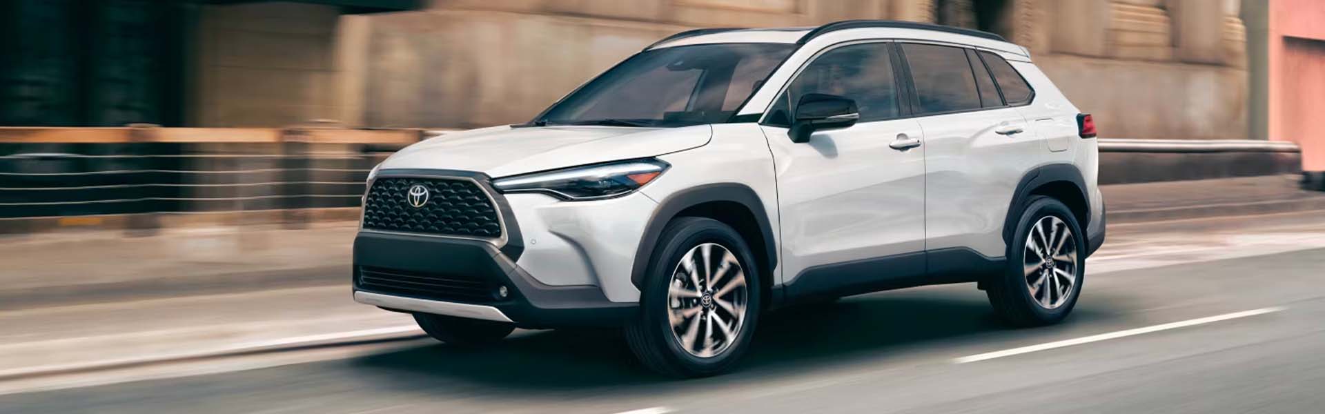 Toyota Corolla Cross 2025 de color blanco circulando por una calle de la ciudad.