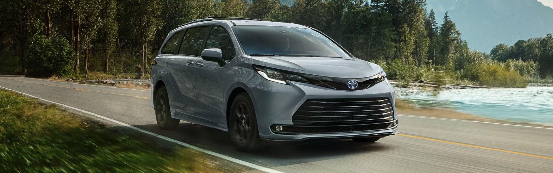El monovolumen Toyota Sienna 2025 recorre una carretera junto a un lago.